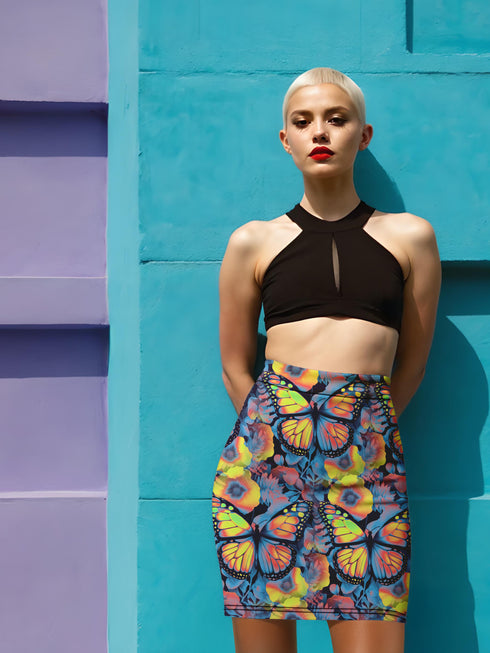 High-waisted bodycon mini skirt with an allover print of rainbow monarch butterflies and colorful tropical flowers on a dark background. Soft, stretchy poly-spandex fabric hugs the body for a flattering fit. Styled for rave, Y2K, and festival outfits. Sizes XS to XL.